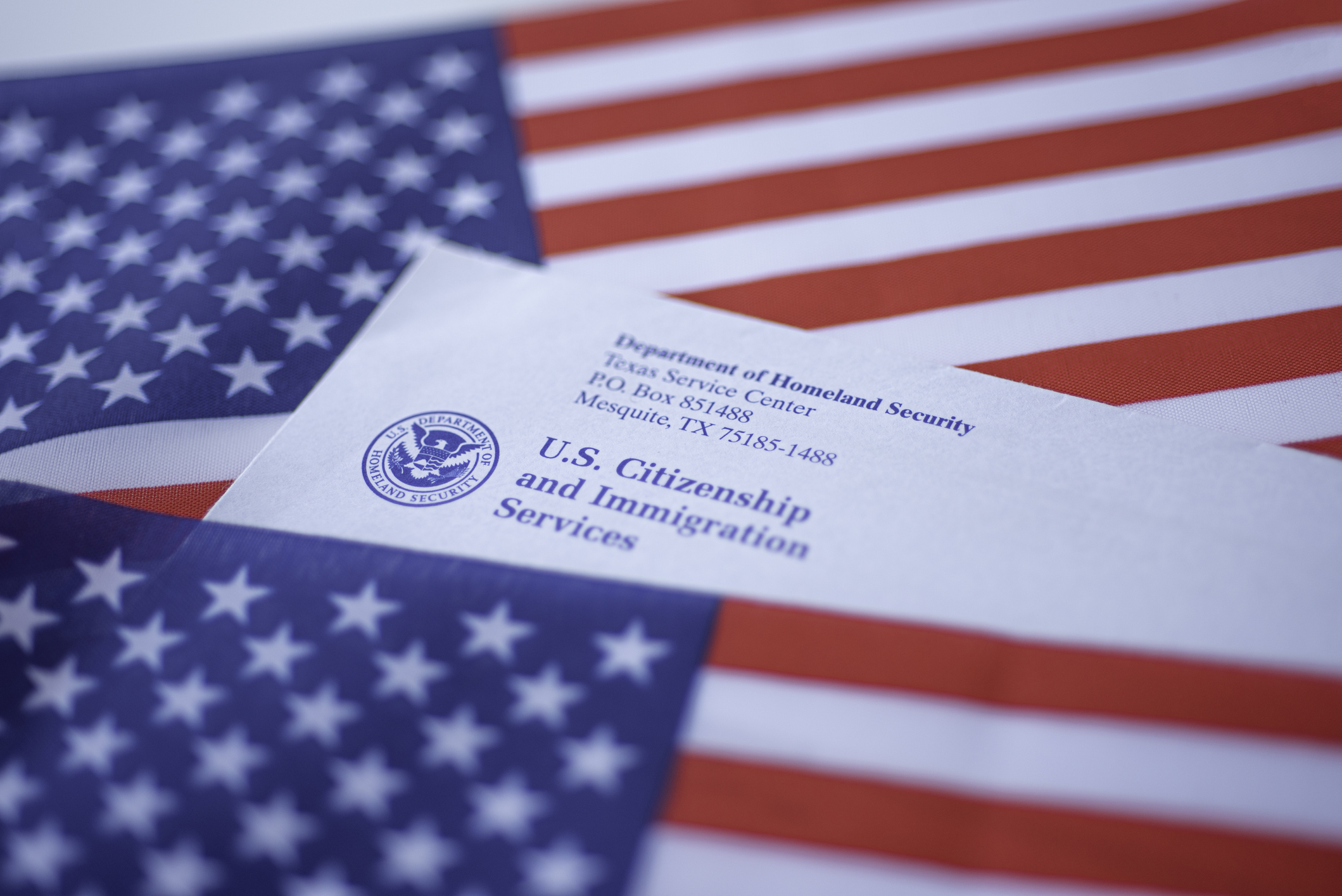 Washington, DC, USA - September, 16, 2019: Letter (Envelope) from USCIS covered in flags of USA. Close up view.